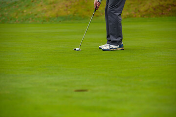 Obraz premium Close-up of a golf player who with a putt pocket the ball on the green