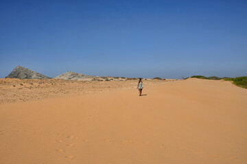 Fototapeta na wymiar Woman walking in the desert of Cabo de la Vela, Guajira, Colombia