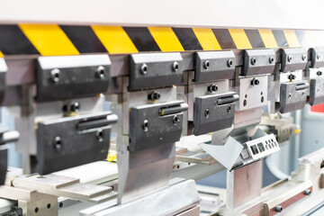 Close up teeth of the semi automatic hydraulic bending machine and the metal sheet or the workpiece during folding forming