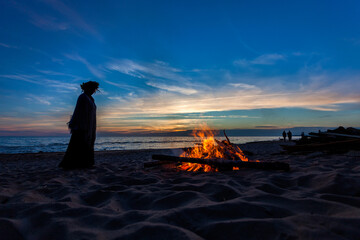 Unrecognisable people celebrating summer solstice with large bonfires on Baltic Sea sandy beach