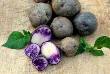Fresh purple potatoes on a wooden surface close-up selective focus.