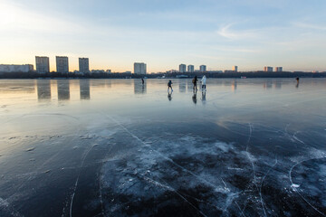 Happy family ice skating outdoors on a reflective fresh ice of frozen Moscow river near the...