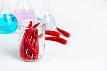 Red chili in a glass, a blurred science test tube in the background.Chili Extract Concept.