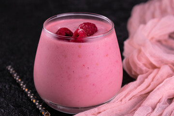 
Raspberry smoothie in a glass on a black background.
Close-up.