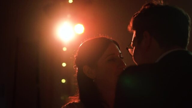 Newly wed couple dance together at their evening party in the golden lights in the dark