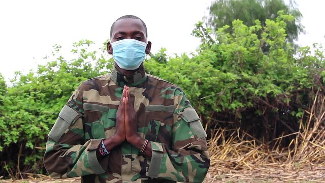 African soldier praying with covid mask on