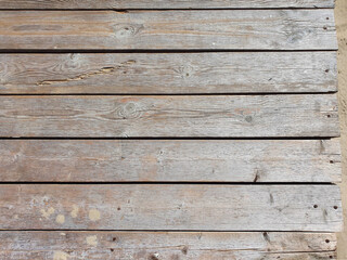 Board Wooden texture background with cracks on sandy beach. Top view, closeup