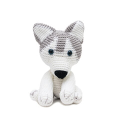 Husky siberiano de pelúcia sentado, feito na técnica de crochê amigurumi visto de frente sobre um fundo branco