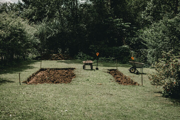 Two wheelbarrows standing in garden near dig site