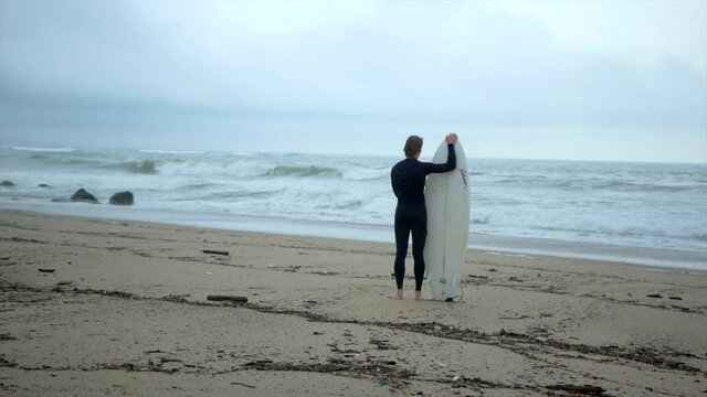 Man holding surf board watching waves crashing on Biaritz beach in France. Slow motion waves. 

1080P 200FPS 10bit SLOG2-REC709