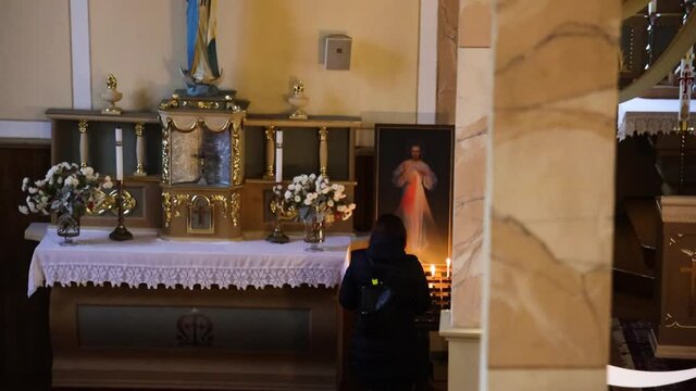 Pan up to a person praying next to the Jesus poster
