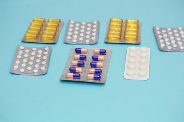 Various multicolored pills (fish oil) and vitamins on a blue background. Health care concept