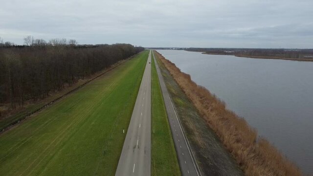 Overhead drone view on a levee with a road and a lake on the side. The levee is located on the shore of the Ketelmeer in Flevoland, The Netherlands
