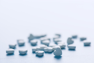 heart-shaped tablets on blue background. medicine, cardiology, health. with copy space