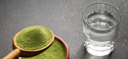 Freeze-dried wheatgrass powder and glass of water.