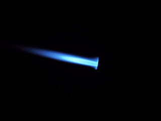 The glow of a gas lighter torch in the dark.
