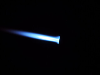 The glow of a gas lighter torch in the dark.