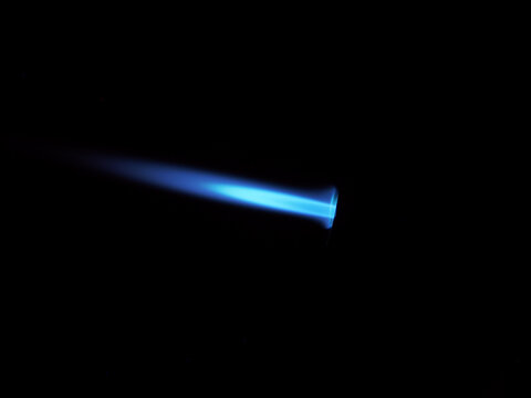 The glow of a gas lighter torch in the dark.