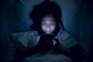 Asian woman playing game on smartphone in the bed at night,Thailand people,Addict social media