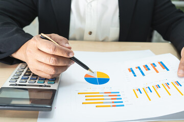 Asian accountant working and analyzing financial reports project accounting with chart graph and...