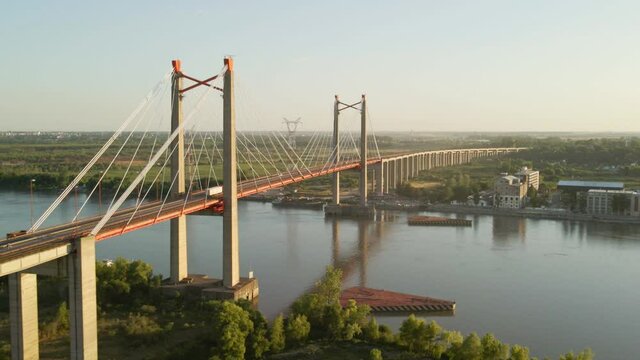 Aerial of a truck transporting cargo over bridge crossing a river at golden hour