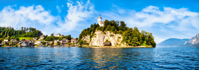 Scenic view of lake Traunsee, city and mountains against blue sky