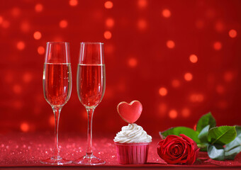 bright red heart on the muffin for Valentine's Day with rose flower and two glasses of champagne