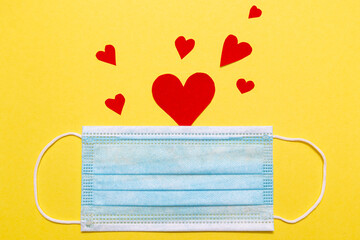 Disposal protective mask and a red heart on a yellow background. Valentines Day theme