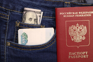 A pack of American hundred dollar bills and Russian rubles in a pocket of blue jeans and an international passport of Russia. Money in your pocket, cash. Travel concept.