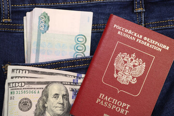 A pack of American hundred dollar bills and Russian rubles in a pocket of blue jeans and an international passport of Russia. Money in your pocket, cash. Travel concept.