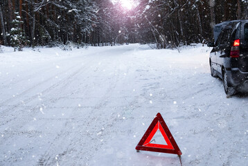 In a snowy forest, a car broke down on the road. A red warning triangle is installed on the snow © Melena-Nsk
