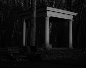 4 column stoa lit by lantern in the middle of park forest