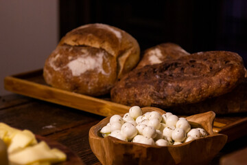 Homemade breads and assorted cheeses exposed on the wooden table.