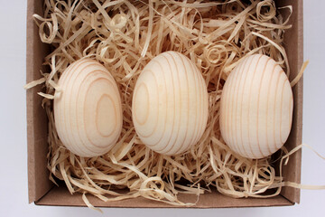 Blank wooden eggs for painting or decoupage in gift box. Easter eggs in a basket on wood table. Top view