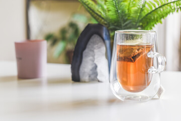 Cup of calming herbal tea with bag in home interior setting