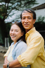 Obraz premium Asian senior couple hugging outdoors in backyard.