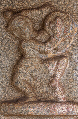 Hampi, Karnataka, India - November 5, 2013: Sri Krishna temple in ruins. Closeup of gray stone barely recognizable damaged male figure,