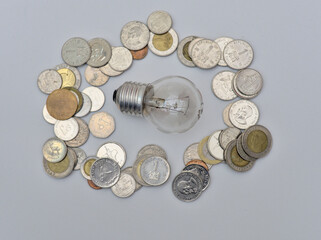 Isolated Bulb with coins. Money spent with light bulbs. Concept of energy efficiency