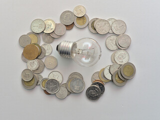 Isolated Bulb with coins. Money spent with light bulbs. Concept of energy efficiency