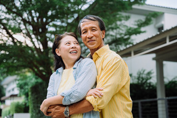 Asian senior couple hugging outdoors in backyard.
