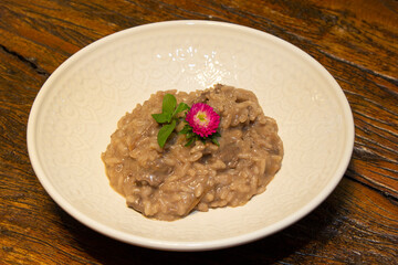 Risotto with chopped pork meat on wooden table in the background