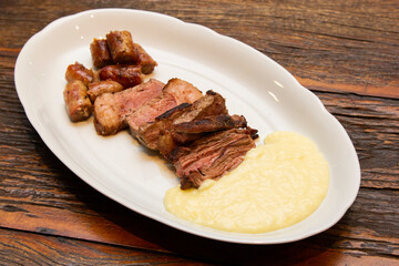Barbecue with anchovy meat and sausage served with aligot.