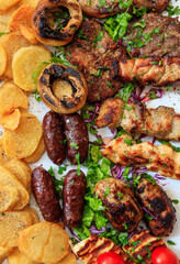 Vertical closeup top view of mixed grilled meat with vegetables and potatoes.
