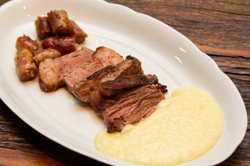 Barbecue with anchovy meat and sausage served with aligot.