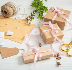 Flat lay of gift boxes and invitations on a white wooden tabletop.