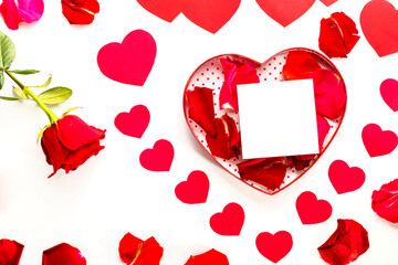 heart made of paper hearts laid out on a white background in the middle of a cardboard heart with rose petals and a note next to the rose flower copy space.