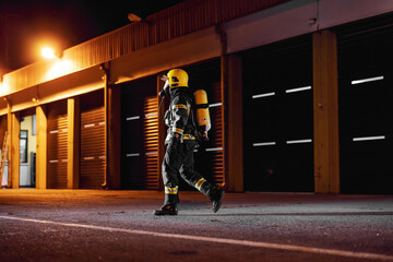 Brave fireman in protective uniform with full equipment running to taking care of fire.