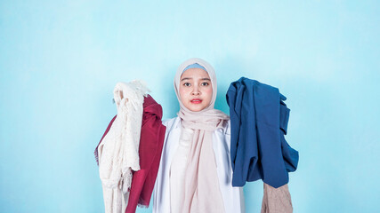 Asian Muslim Woman choosing clothes at home wardrobe - clothing, fashion, style and people concept
