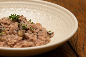 Mushroom risotto, on the wooden table.