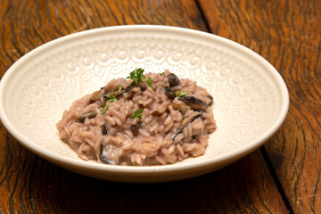 Mushroom risotto, on the wooden table.